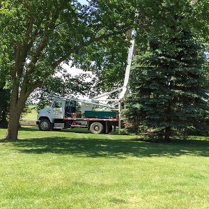 Green and white waskosky well drilling truck in a backyard
